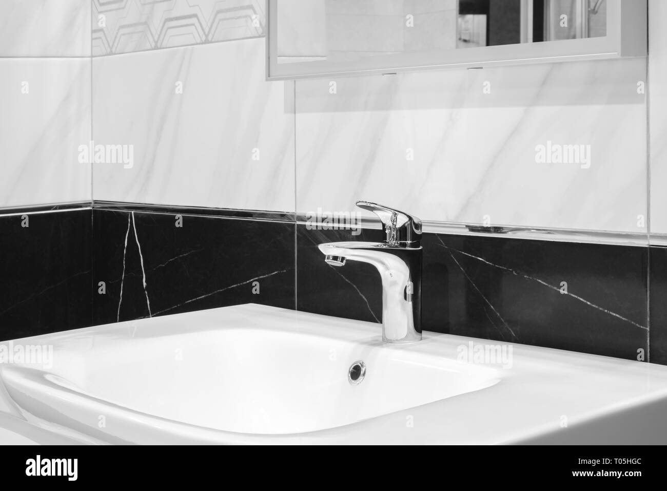 Mélangeur robinet de luxe sur un évier blanc dans une belle salle de bains gris Banque D'Images