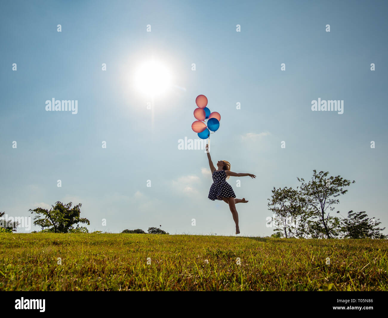 Female ballet dancer holding balloons flying loin Banque D'Images