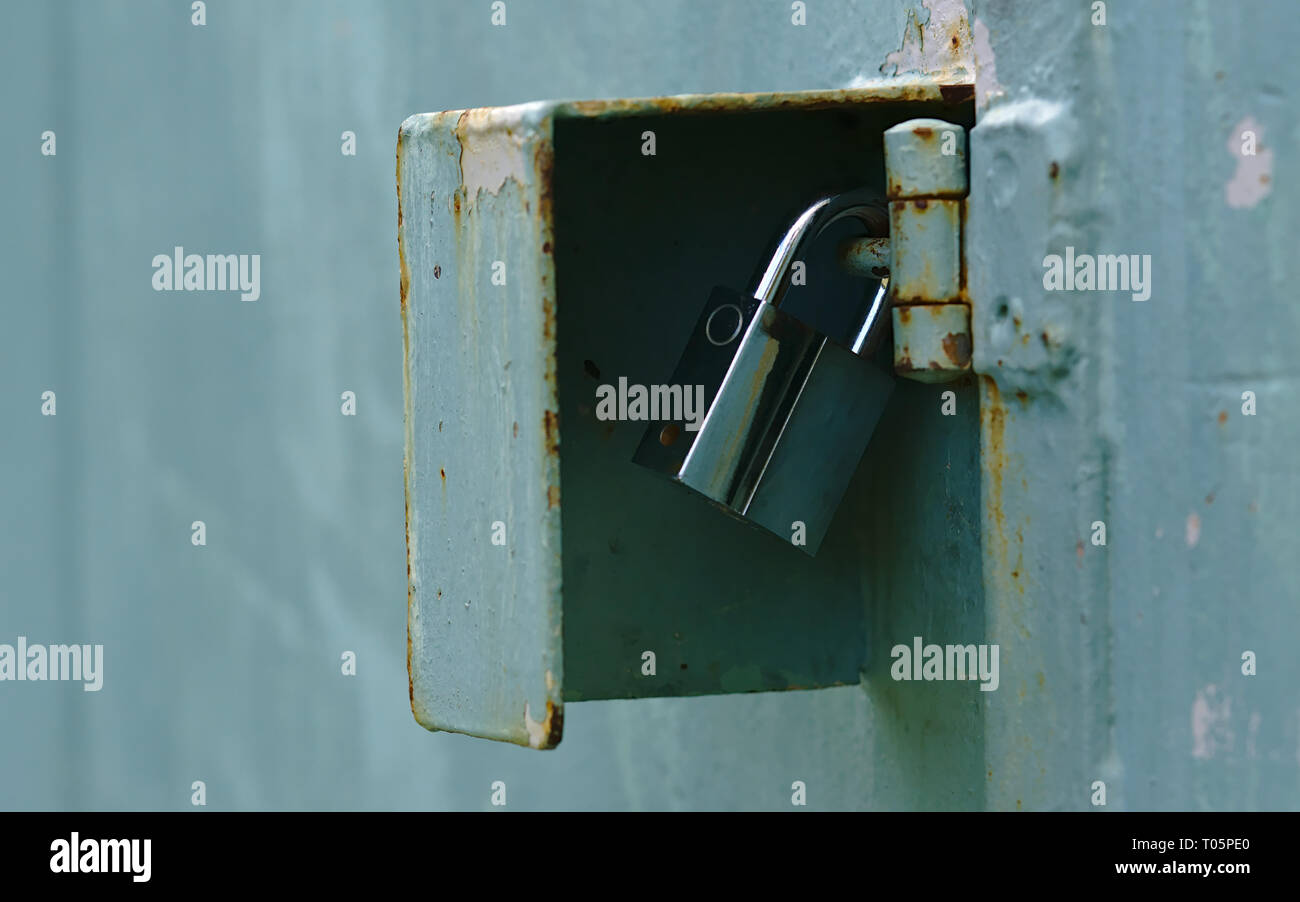 Vue rapprochée d'argent fixation cadenas charnière de porte bleu léger corrosif Banque D'Images