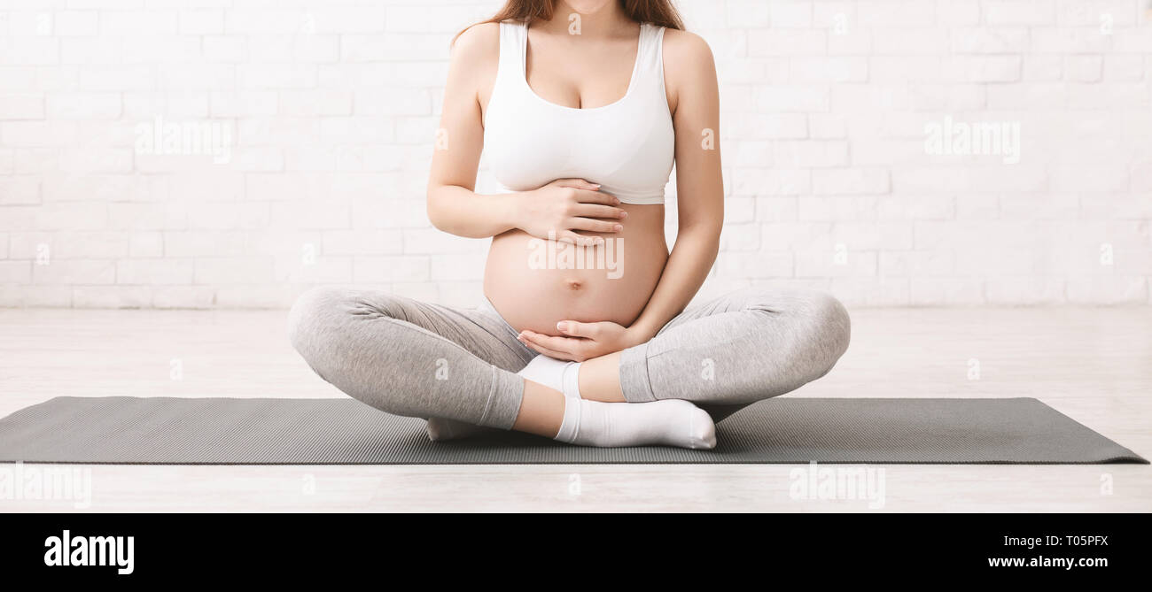 Pregnant woman meditating in lotus position à Accueil Banque D'Images