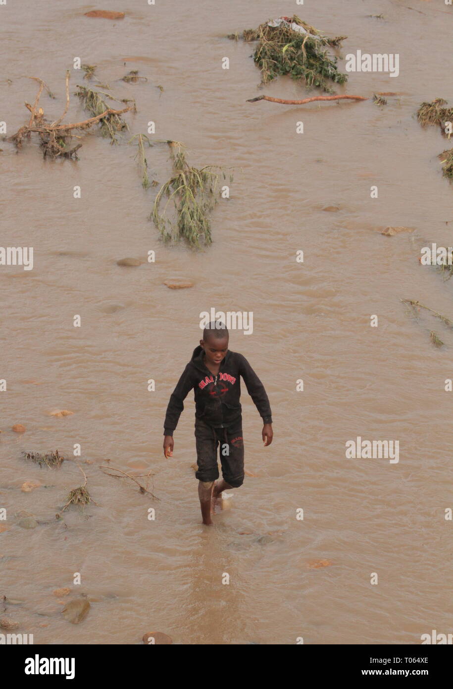 Chimanimani, Zimbabwe. Mar 17, 2019. Un garçon marche dans une rivière en crue dans la région de Chimanimani, la province de Manicaland, au Zimbabwe, le 17 mars 2019. Au moins 31 personnes ont été confirmées décédées tandis que des dizaines d'autres sont toujours portées disparues dans le cyclone tropical Idai fait des ravages dans le sud-est du Zimbabwe, le gouvernement a déclaré samedi soir. Credit : Shaun Jusa/Xinhua/Alamy Live News Banque D'Images