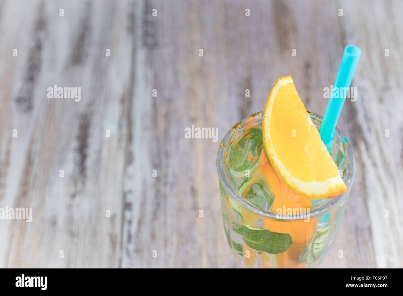 Les agrumes boisson rafraîchissante dans un gobelet en verre sur une table en bois. été cocktail rafraîchissant. Une saine alimentation, boissons. orange et menthe de l'eau glacée. Copy space Banque D'Images