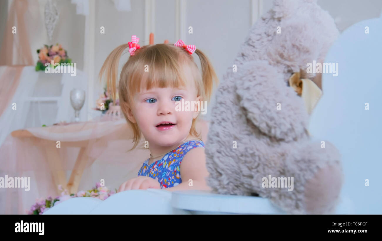 Petite fille jouant avec cheval à bascule en bois blanc et l'ours doll Banque D'Images