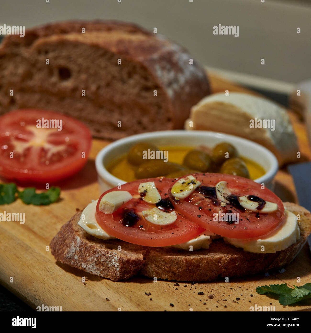 Pain au levain de seigle avec tomates mozzarella olives et rustique avec vue latérale du couteau avec un peu de lumière naturelle Banque D'Images