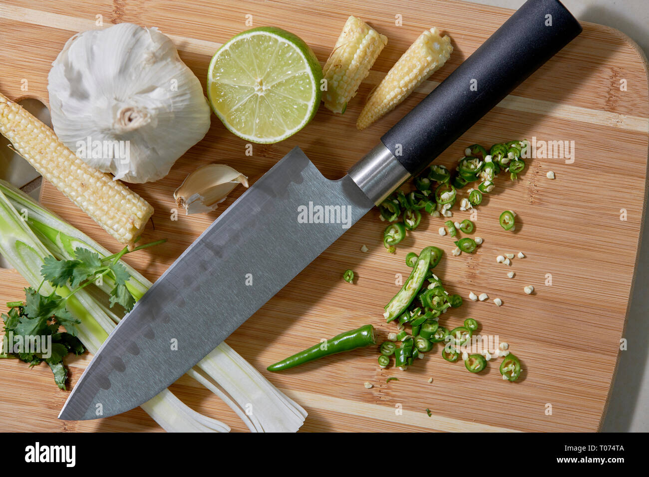 Piments Thaï asiatique et les légumes les ingrédients sur planche à découper avec Couteau Santoku Banque D'Images