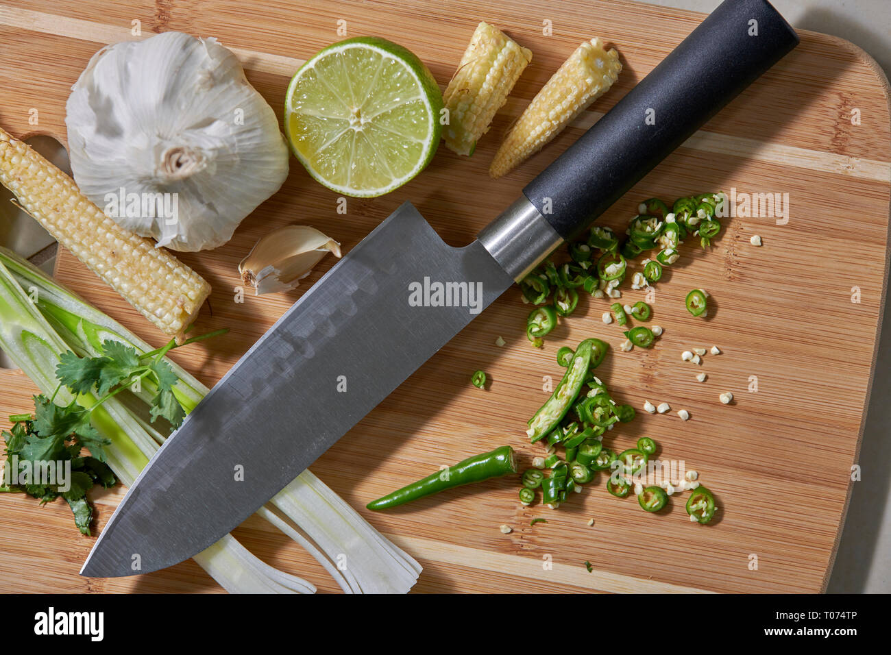 Piments Thaï asiatique et les légumes les ingrédients sur planche à découper avec Couteau Santoku Banque D'Images