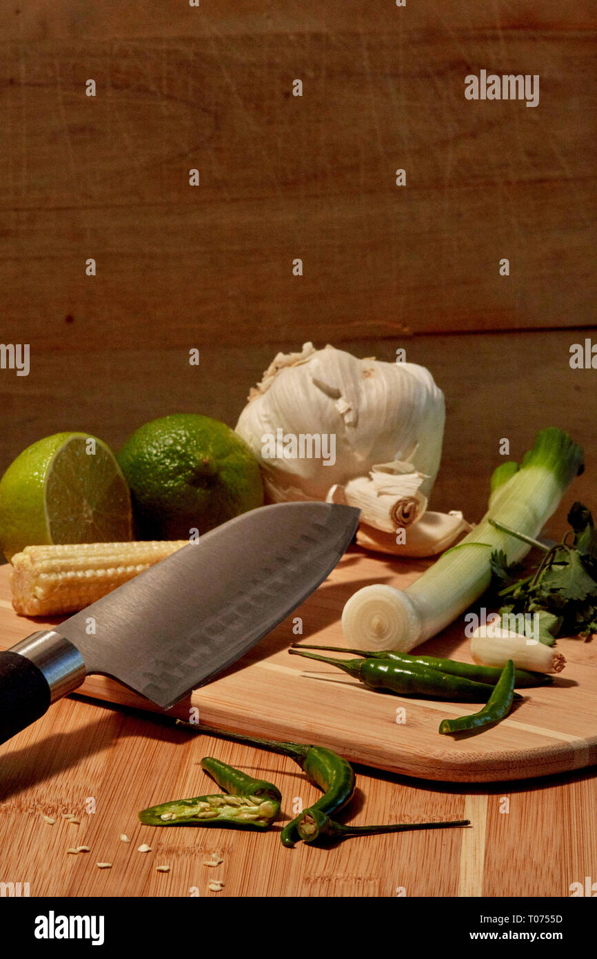 Piments Thaï asiatique et les légumes les ingrédients sur planche à découper avec Couteau Santoku Banque D'Images