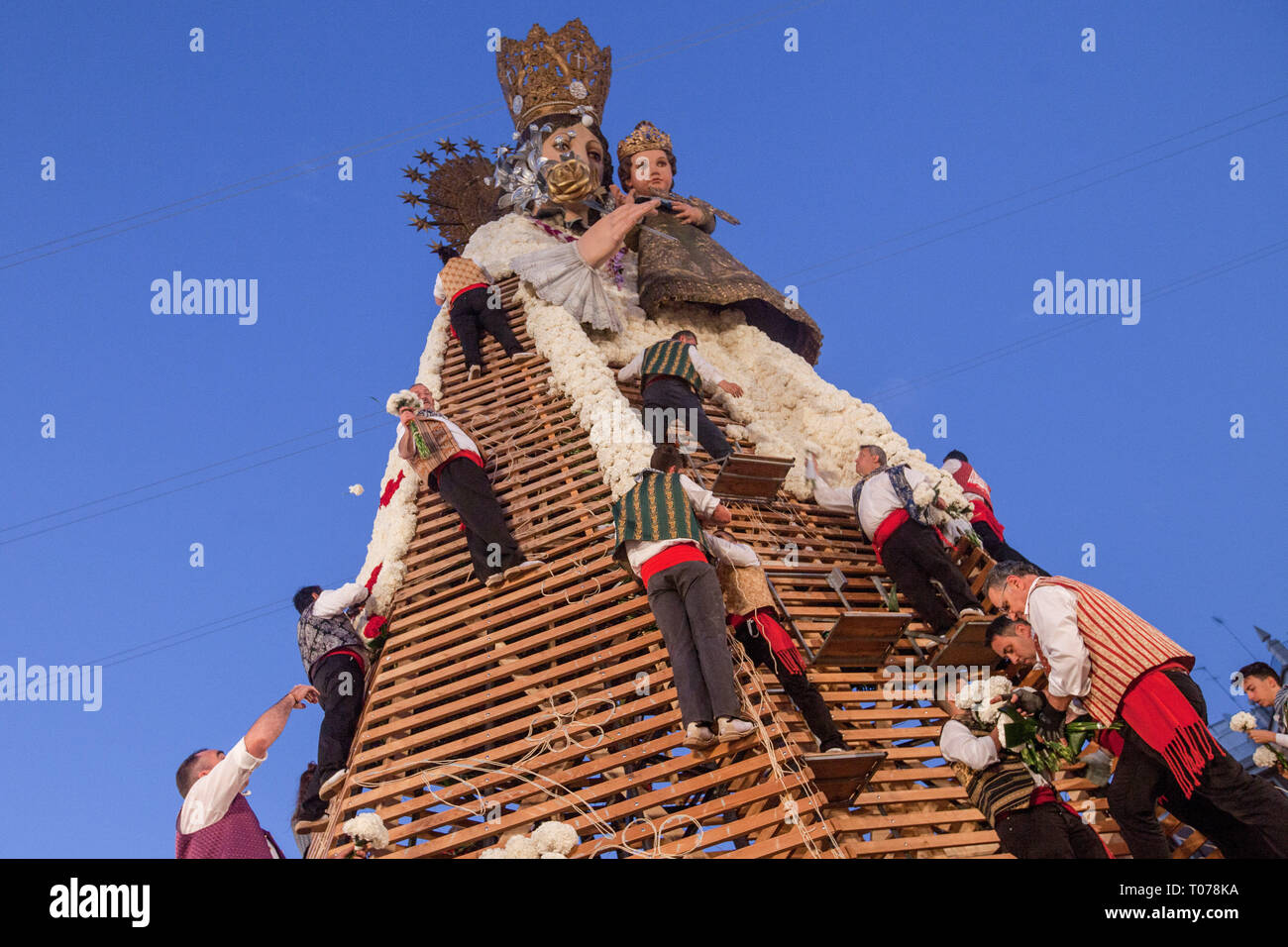 Les hommes habillés en costume traditionnel, travail sur grand modèle de Virgen de los Desamparados (La Vierge des Réprouvés) couvrant de fleurs pendant Fallas de Valence. Les Fallas sont immenses sculptures représentant des personnages célèbres ou des événements actuels dans les rues de Valence qui peut être vu au cours de la 'Las Fallas' Festival, les sculptures seront ensuite graver le 19 mars 2019 en hommage à Saint Joseph, saint patron de la guilde des charpentiers. Banque D'Images