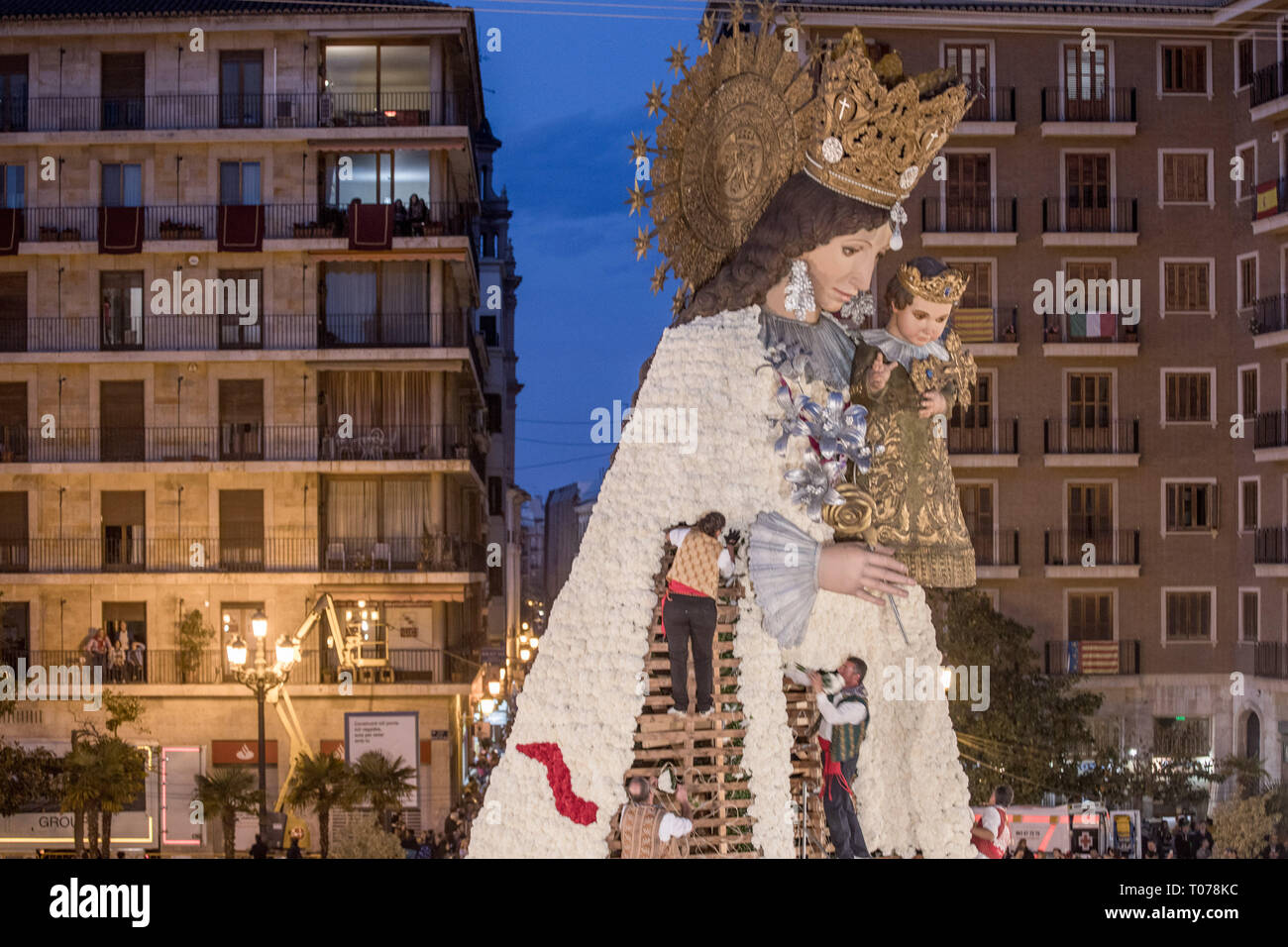 Les hommes habillés en costume traditionnel, travailler à la base d'un grand modèle de Virgen de los Desamparados (La Vierge des Réprouvés) couverte de fleurs au cours de Fallas de Valence. Les Fallas sont immenses sculptures représentant des personnages célèbres ou des événements actuels dans les rues de Valence qui peut être vu au cours de la 'Las Fallas' Festival, les sculptures seront ensuite graver le 19 mars 2019 en hommage à Saint Joseph, saint patron de la guilde des charpentiers. Banque D'Images