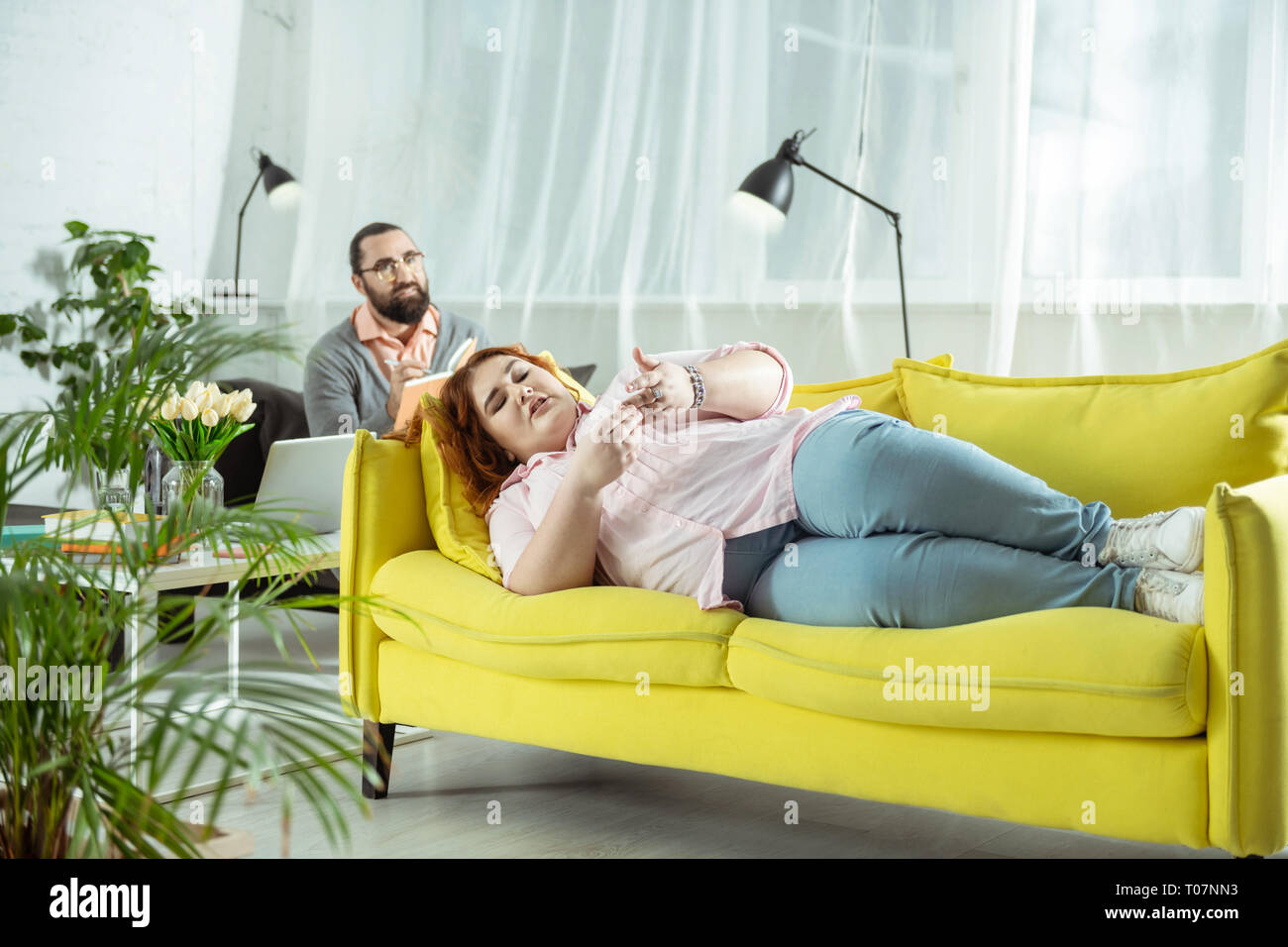 Surpoids détendue girl lying on sofa jaune Banque D'Images