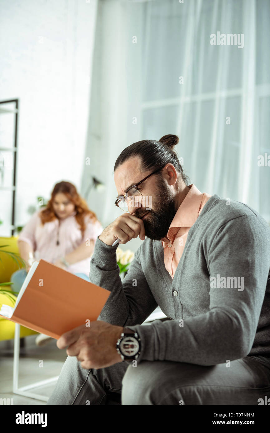 L'homme positif ravie brunette ses notes de lecture Banque D'Images
