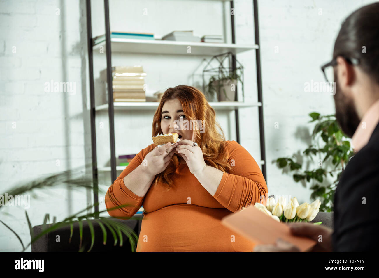 Fille dodue faim manger un gâteau avec plaisir Banque D'Images
