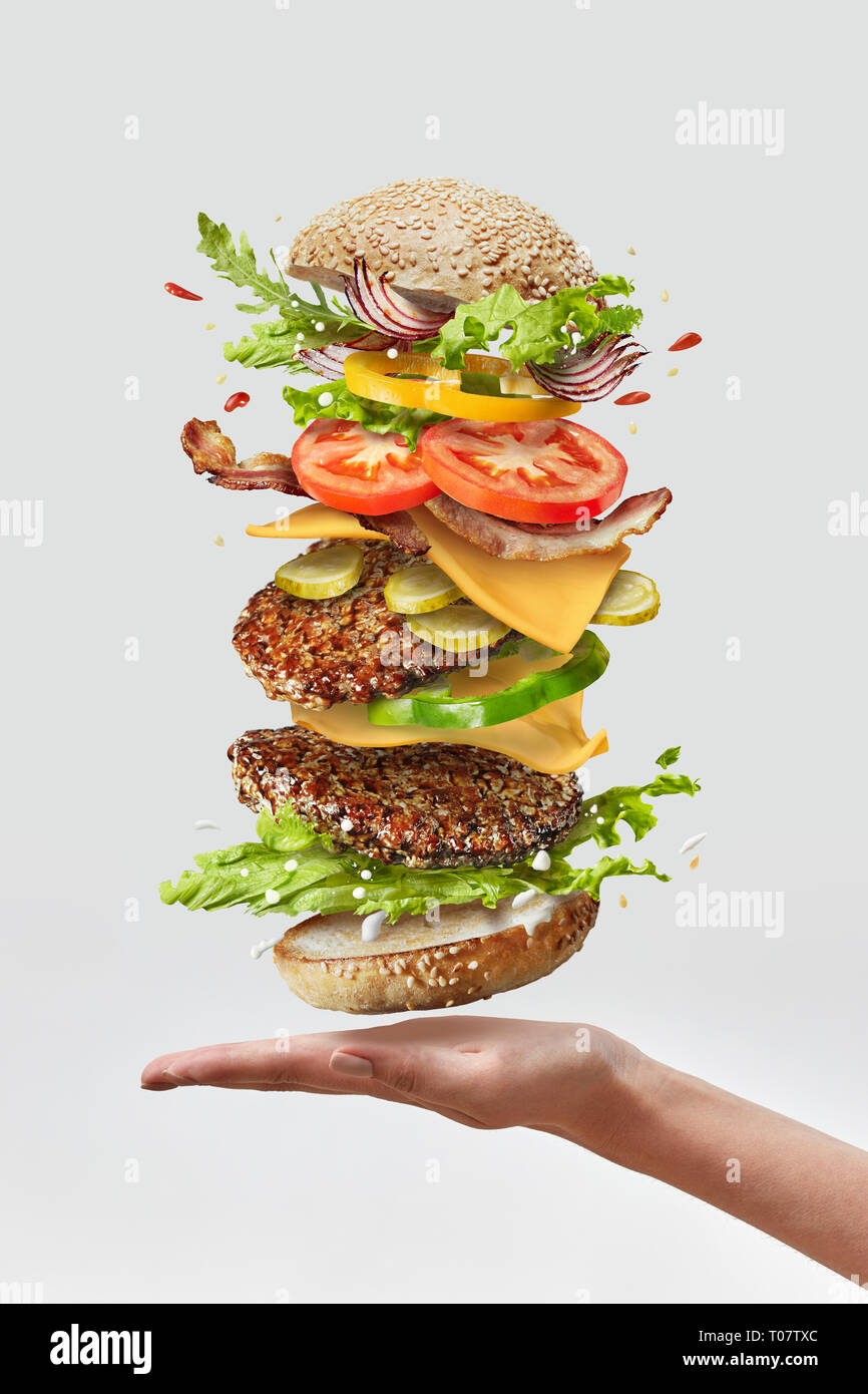 Deliciouse burger fait maison sur une femme qui part avec des ingrédients frais sur un fond blanc. Copier l'espace. Banque D'Images