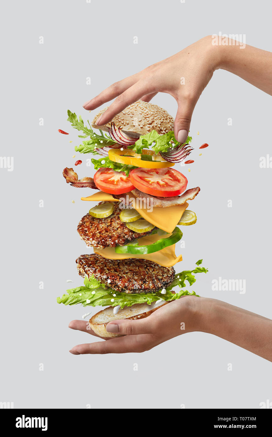 Girl's hands hold big tasty burger fait maison avec des ingrédients natutal sur fond blanc. Copier l'espace. Banque D'Images