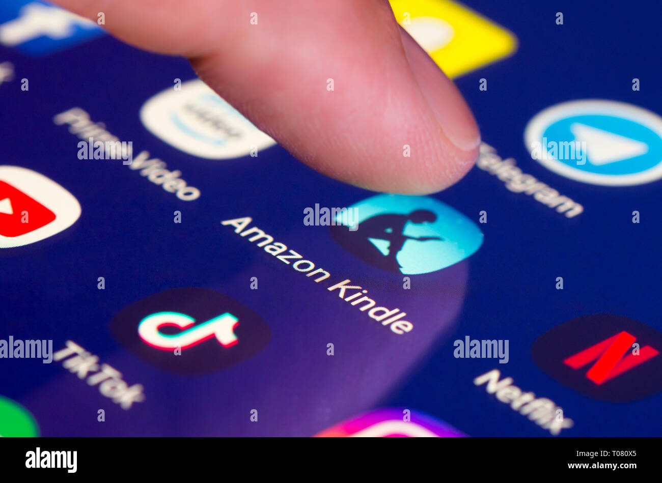 Doigt appuyant sur Amazon Kindle app icône sur un écran tactile sur une tablette ou un téléphone mobile. Le chargement de l'application Amazon Kindle. Kindle raccourci. Banque D'Images