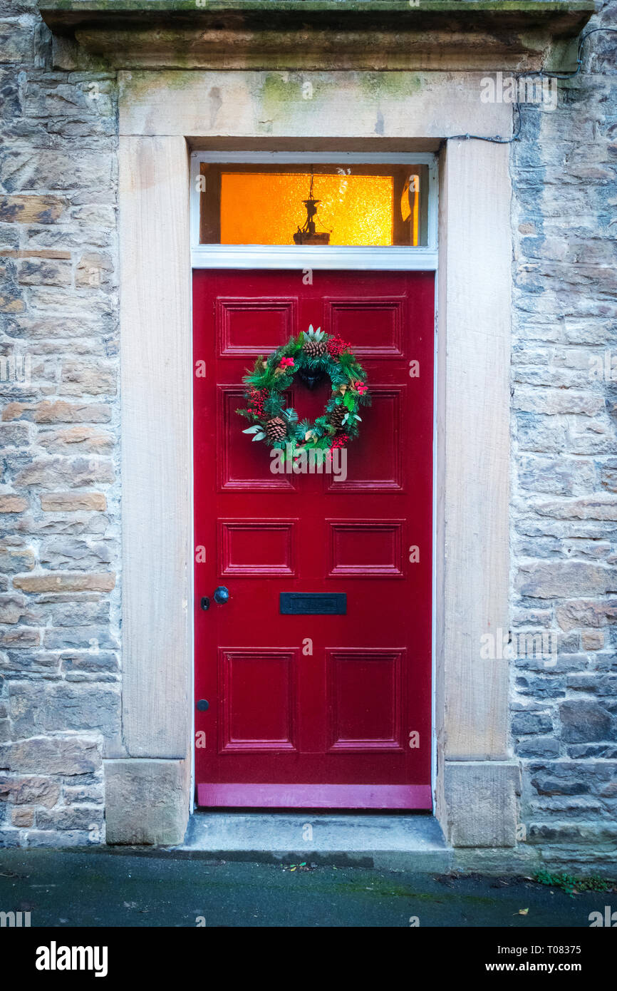 Maison ancienne en pierre avec un style géorgien peint rouge et porte une couronne de Noël qui s'accrochent à lui Banque D'Images