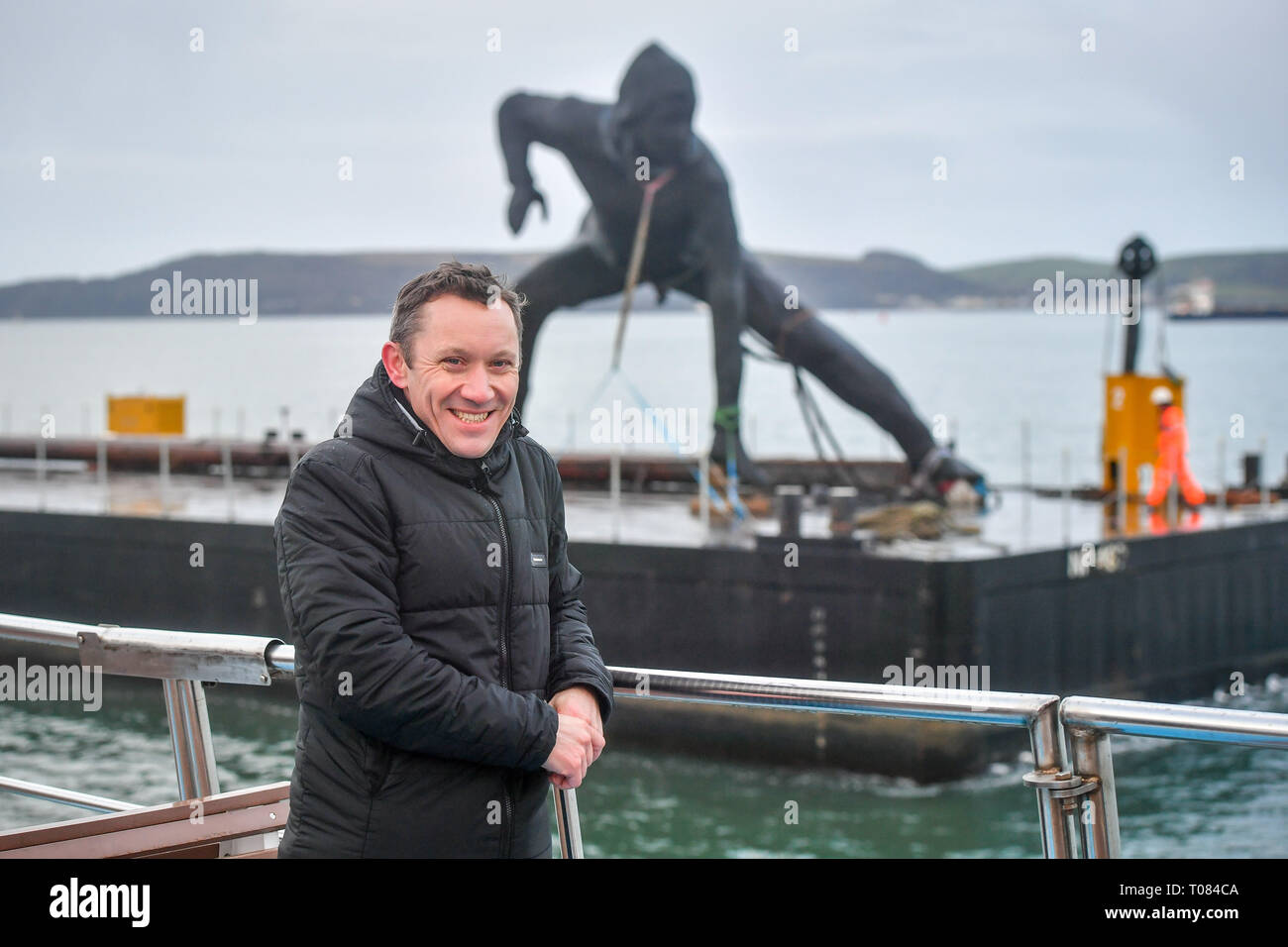 L'artiste Joseph Hillier sur un bateau à côté de sa sculpture, Messenger, la plus grande sculpture en bronze au Royaume-Uni, comme il arrive à Plymouth Sound par barge comme il fait son chemin pour être installé à l'extérieur du Theatre Royal, plymouth Devon. Banque D'Images