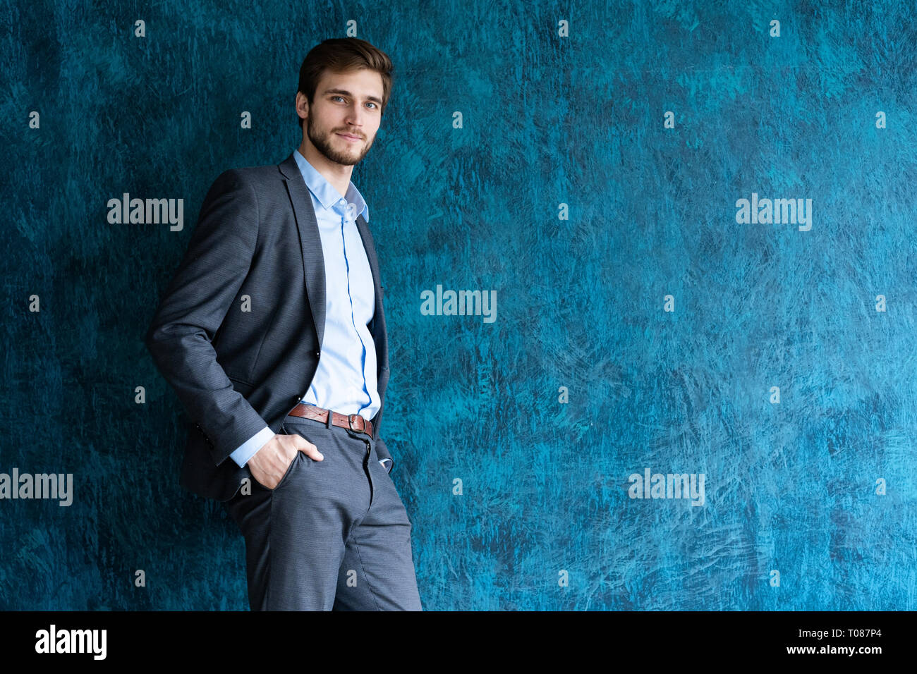 Portrait of handsome young man standing contre mur bleu avec copie espace. Banque D'Images
