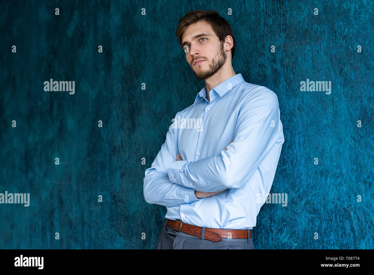 Portrait of handsome young man standing contre mur bleu avec copie espace. Banque D'Images