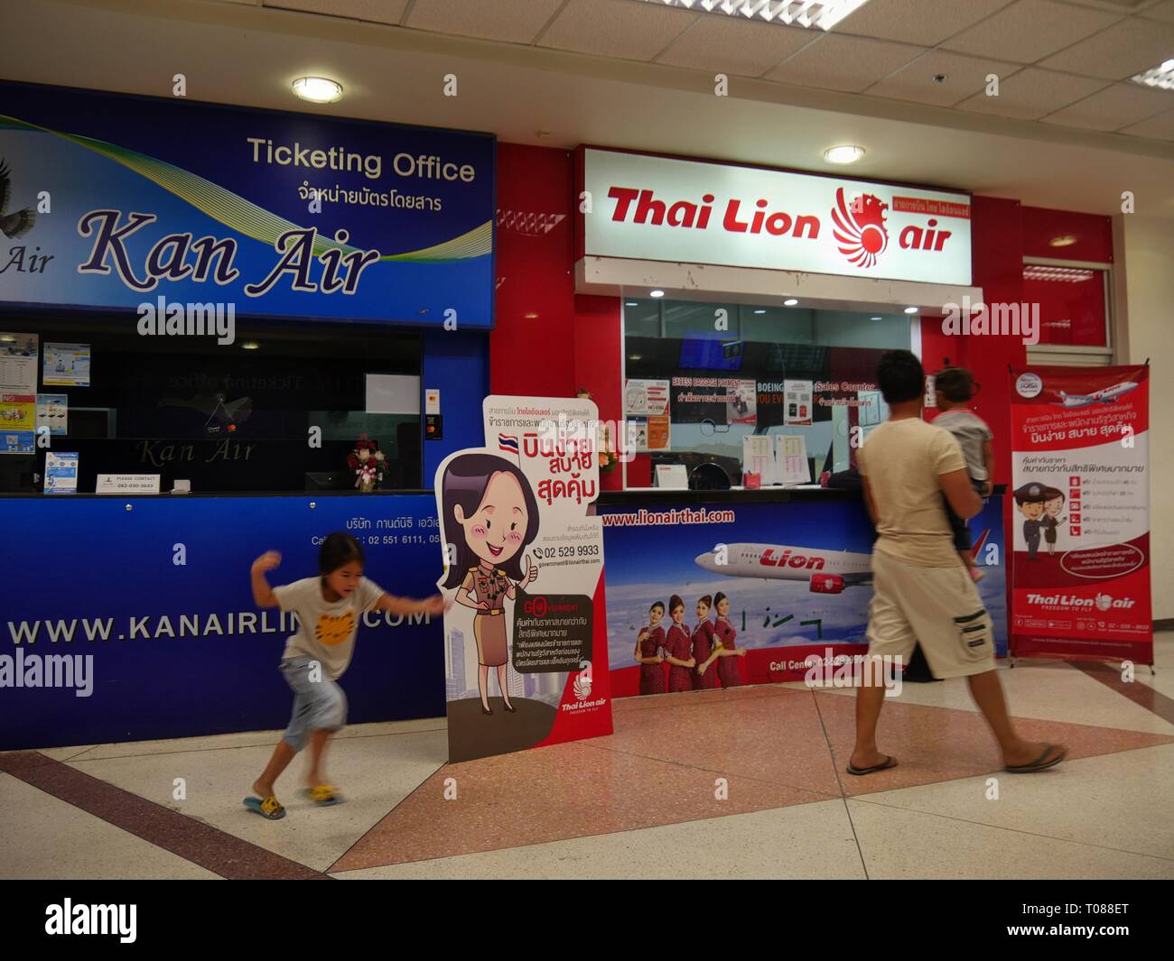 CHIANG MAI, THAÏLANDE —MARS 2018: Un enfant court devant les bureaux de billetterie de Kan Air et Thai Lion Air à l'aéroport international de Chiang Mai. Banque D'Images