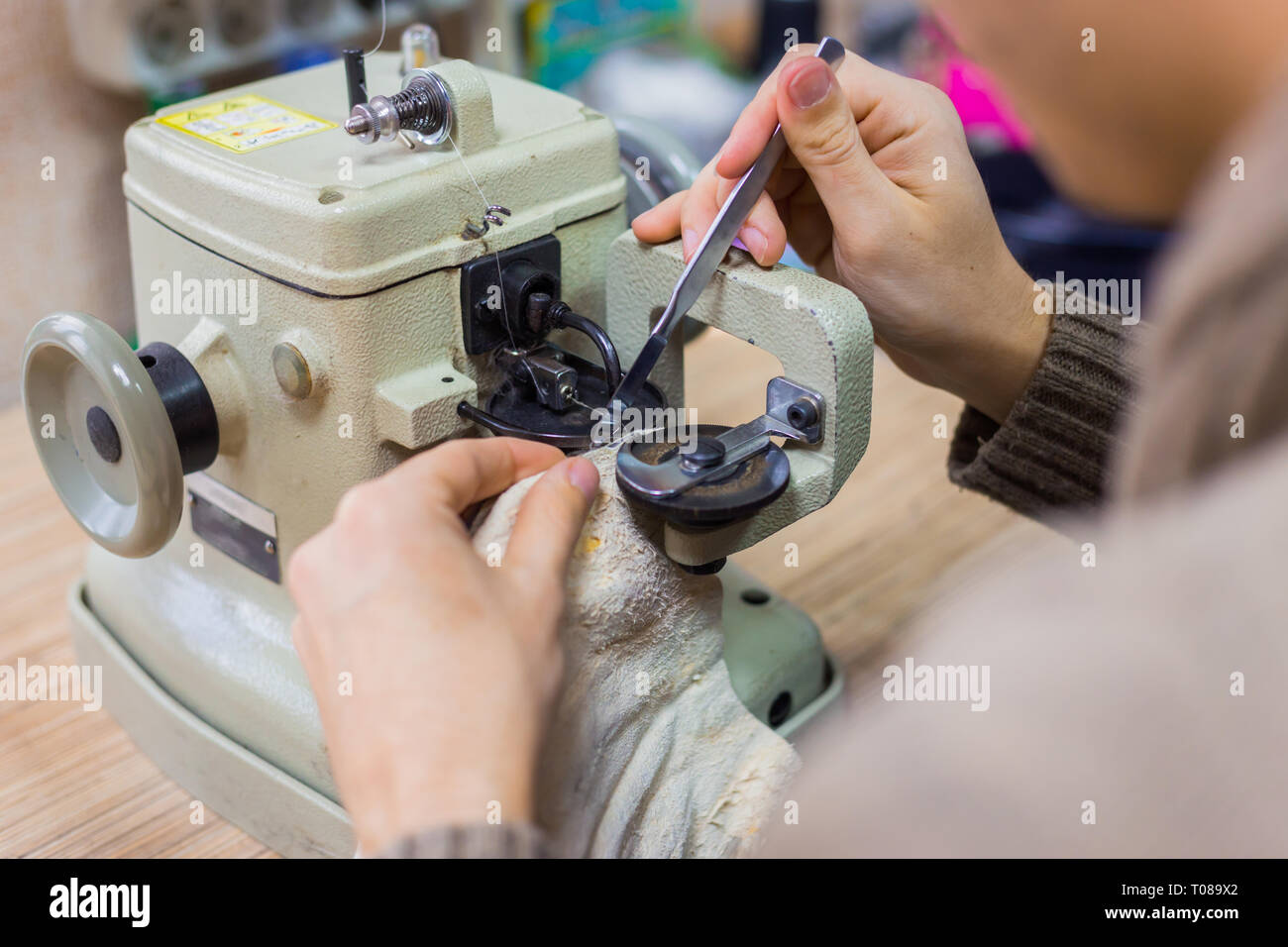 Professionnel hommes skinner, fourreur à l'aide de la machine à coudre spéciale pour coudre la peau de fourrure à l'atelier, atelier. La mode et le travail du cuir concept Banque D'Images