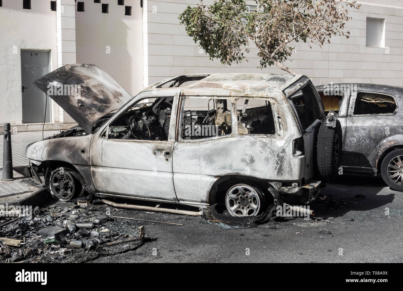 Brûlé de voitures qui étaient garés à côté du conteneur d'ordures incendiés par des vandales dans la rue en Espagne Banque D'Images