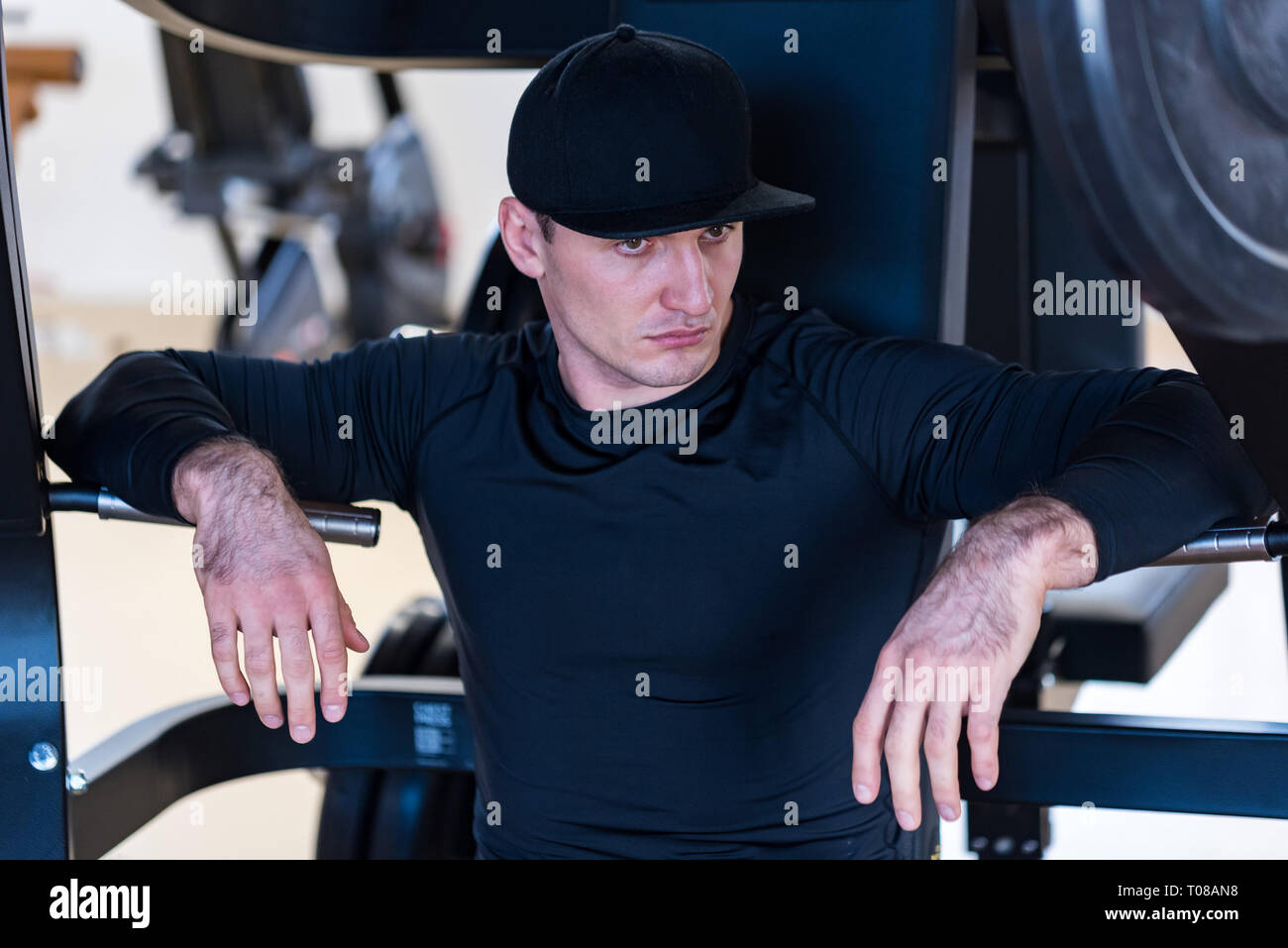 Portrait de l'athlète masculin wearing cap sitting at gym Banque D'Images