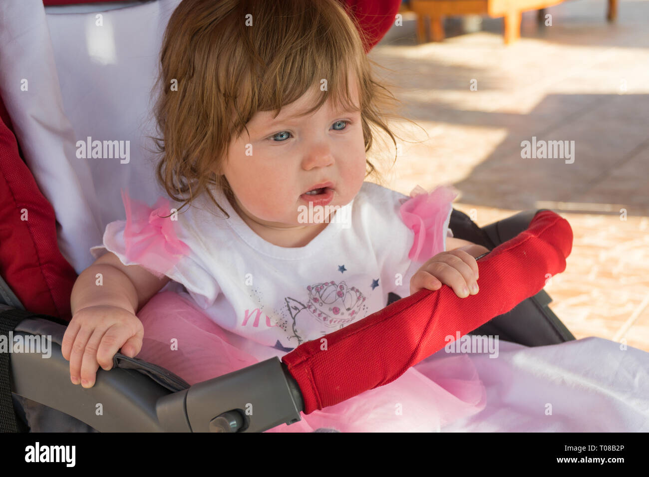 Peu cute baby girl sitting in stroller Banque D'Images