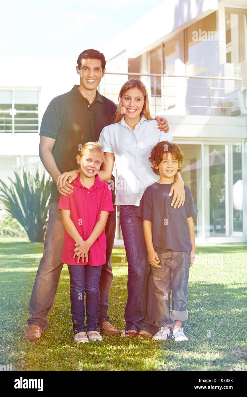 Happy Family est debout avec deux enfants en face de la maison dans le jardin Banque D'Images