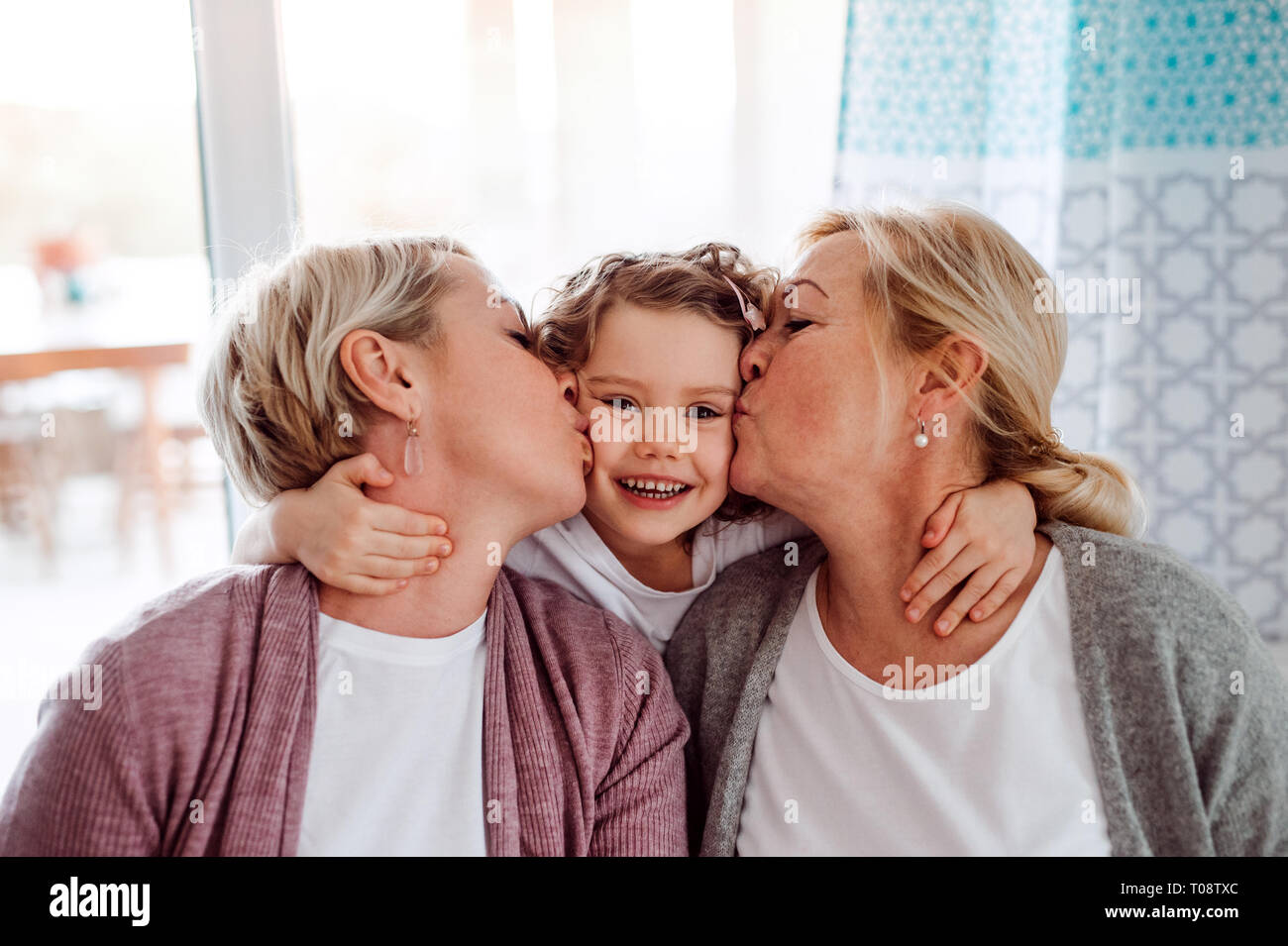 Un portrait de petite fille avec la mère et grand-mère à la maison, en l'embrassant. Banque D'Images