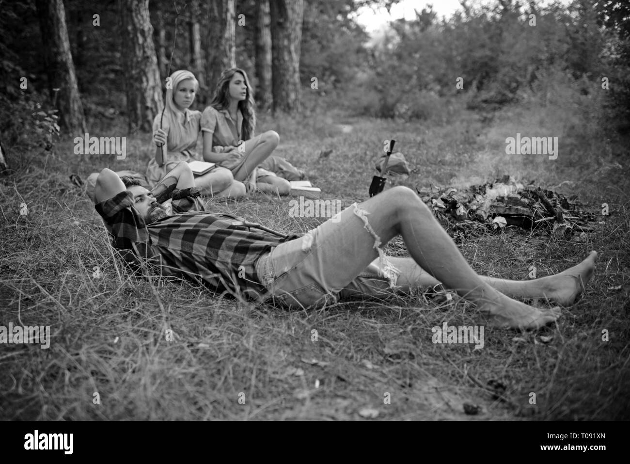 Homme barbu en chemise de bûcheron couché sur l'herbe et à regarder vers le ciel, de l'unité avec la nature concept. Groupe d'amis camping en forêt Banque D'Images