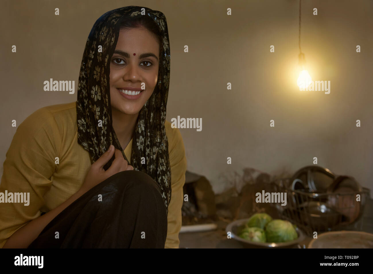 Close up of a smiling woman sitting in rural la cuisson la cuisine sur bois avec des ustensiles et des légumes sur le sol. Banque D'Images