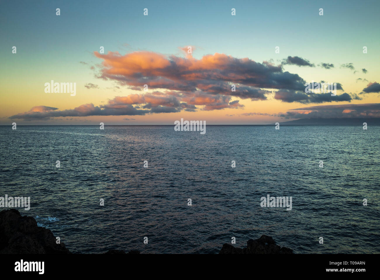 Les nuages au-dessus de l'Atlantique rouge par le lever du soleil avec l'île de La Gomera à l'horizon, à l'ouest de Playa San Juan avec la roche volcanique forma Banque D'Images