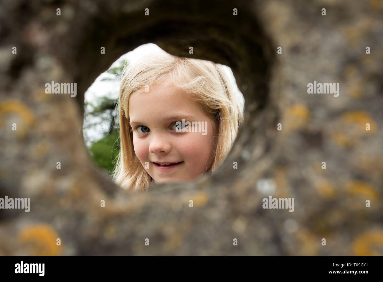 La Grande-Bretagne, l'Angleterre, l'Oxfordshire, Rollright Stones. Jeune fille regarde à travers un trou naturel dans un mégalithe, peut-être un rituel païen datant cen Banque D'Images