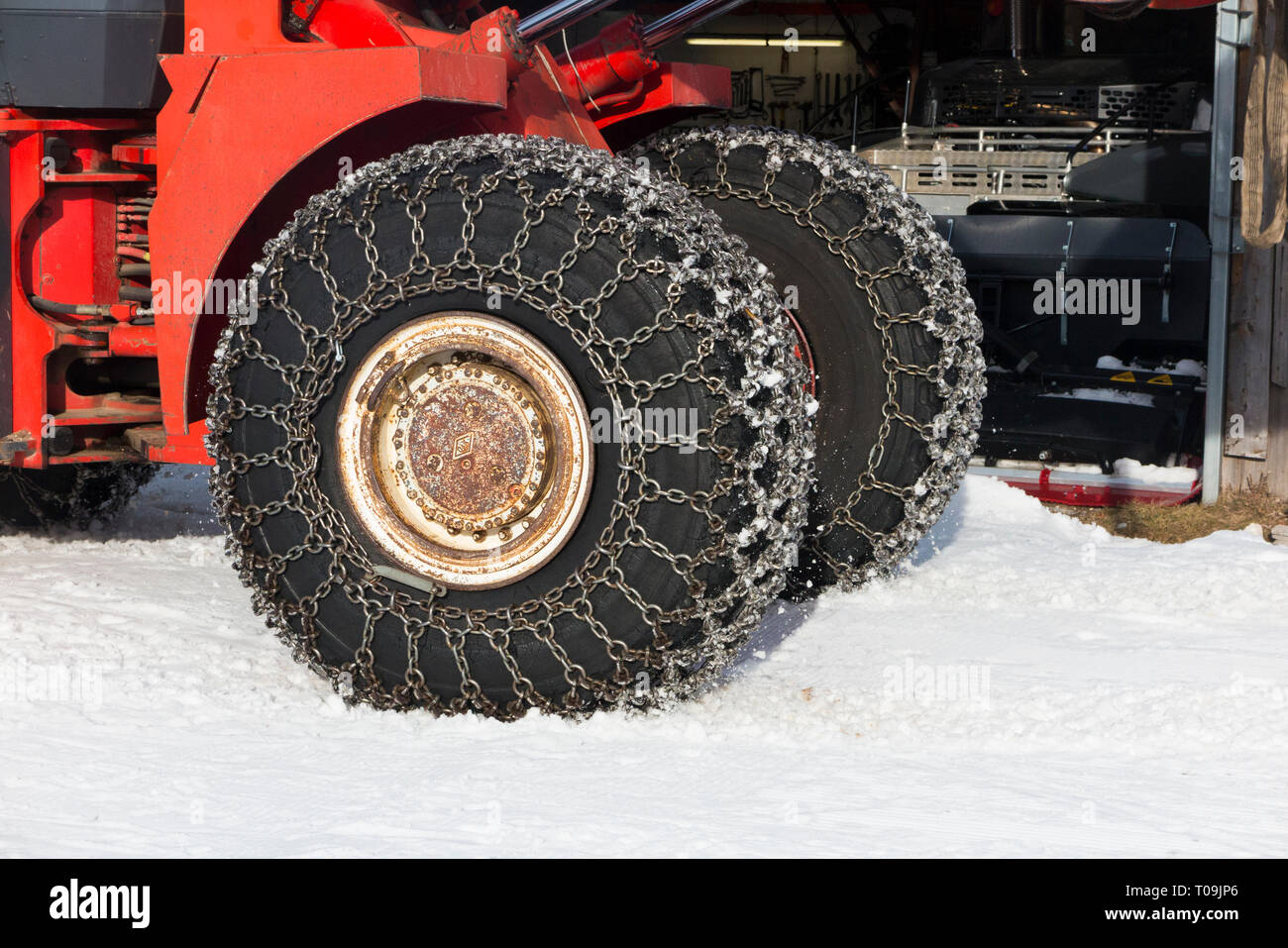 Chaîne à neige/chaînes sur avant et arrière / arrière / Roues / pneus / pneus d'un véhicule commercial, agricole / chargeur sur roues tracteur dans un froid avec chute de neige et de glace. Banque D'Images