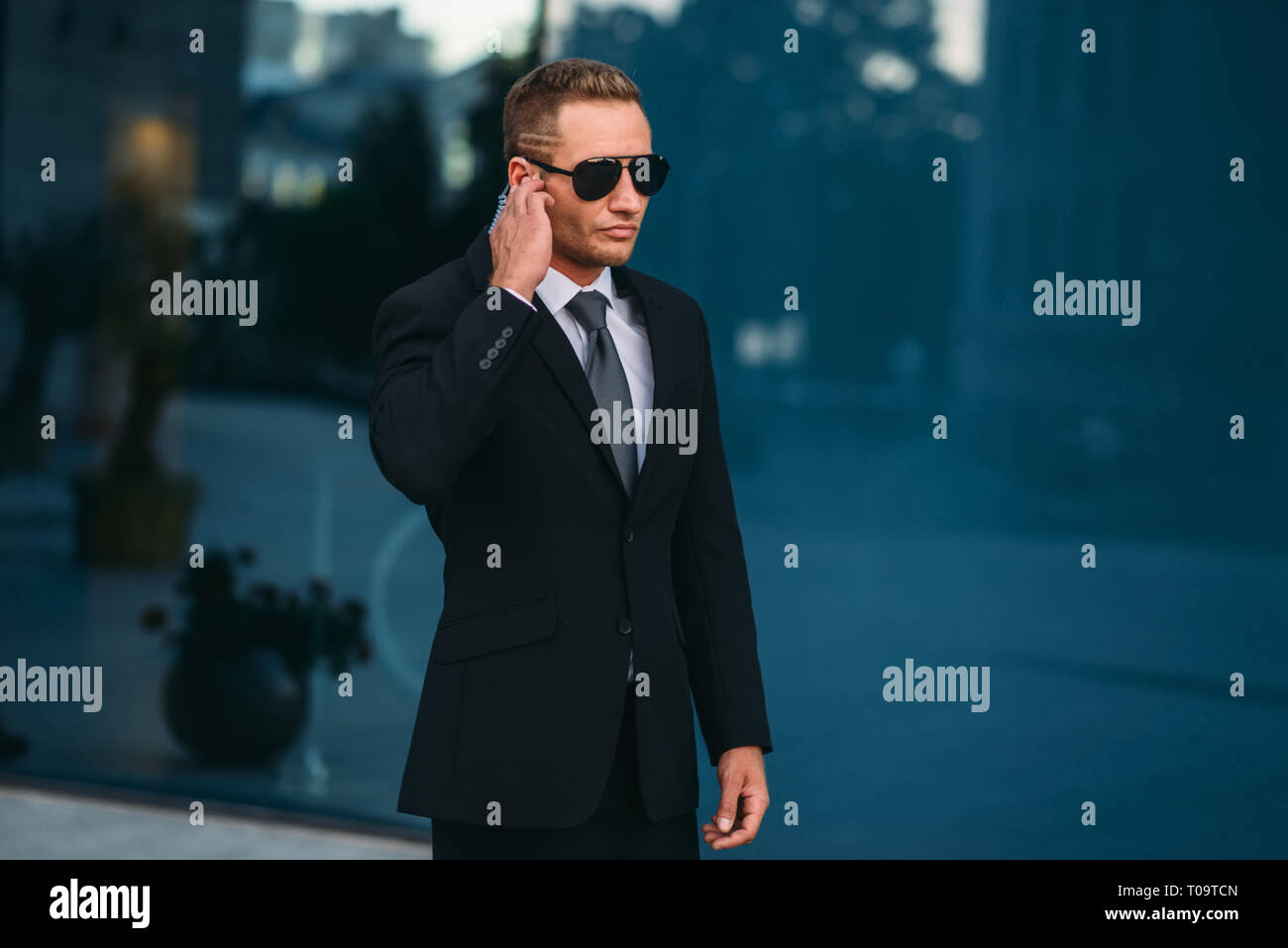 Garde du corps masculin, l'extérieur de l'écouteur de sécurité utilise des outils de communication professionnelle. La garde est une profession à risque. En costume et lunettes de protection Banque D'Images