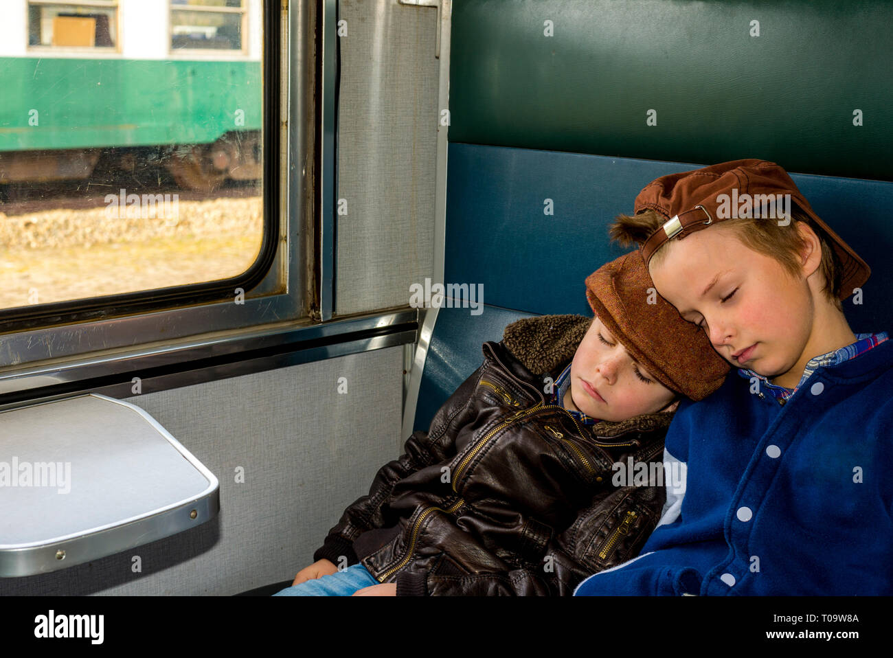 Deux garçons dormant dans un train pendant leur voyage Banque D'Images
