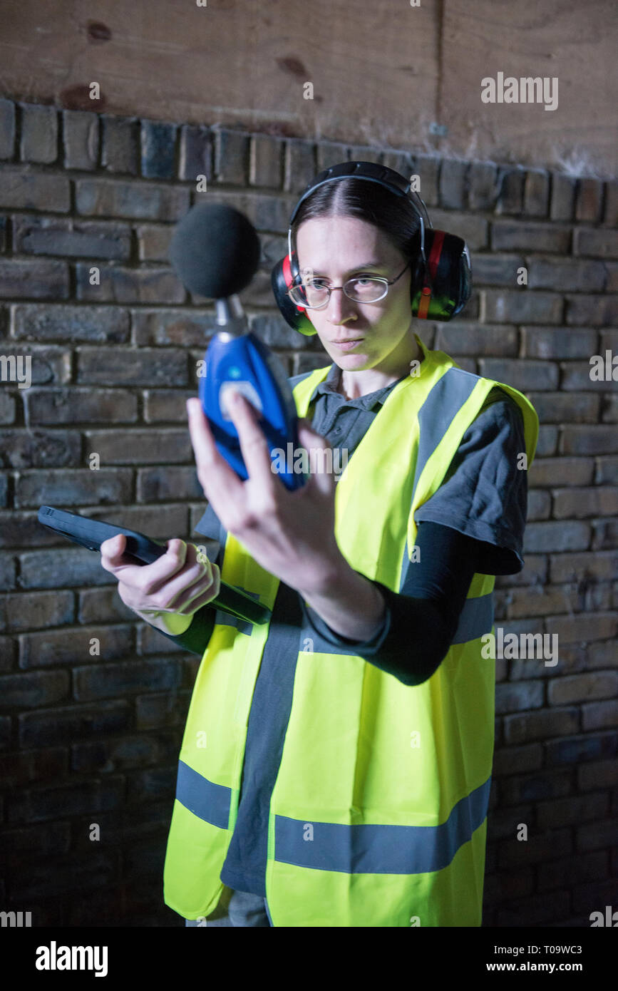 Un arpenteur de l'environnement femmes tests pour le son et le bruit durant une enquête sur un chantier à l'aide d'équipements spécialisés. Banque D'Images