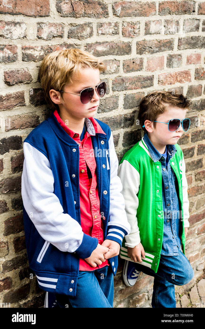 Deux cool kids avec des lunettes appuyé contre un mur Banque D'Images
