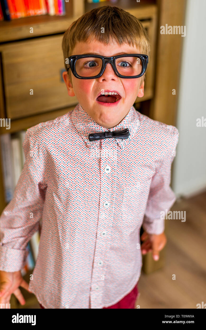 Petit garçon avec des lunettes nerdy geek, rendant les expressions faciales. Banque D'Images