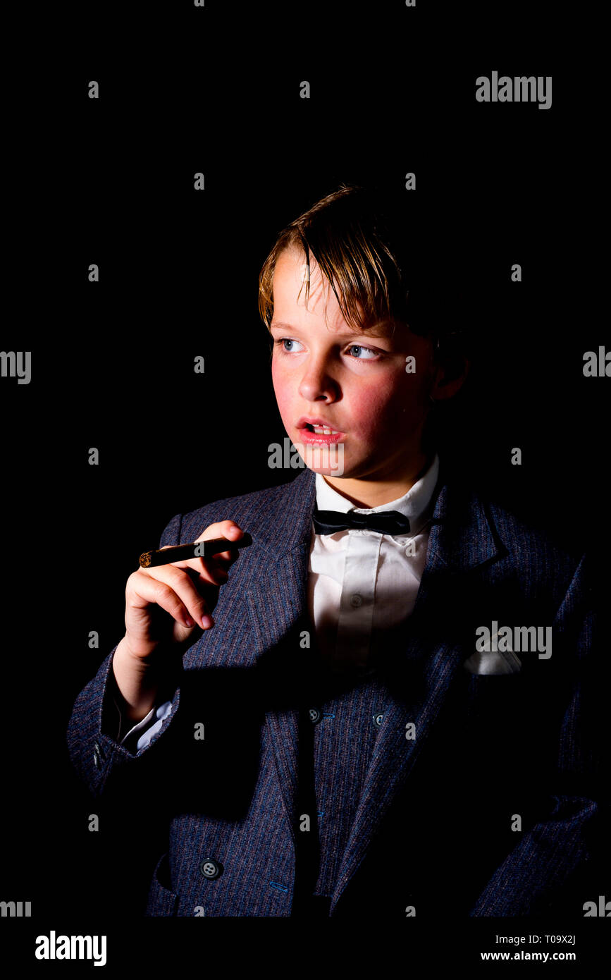 Boy in suit, tenant un cigare. faible image clé. Banque D'Images