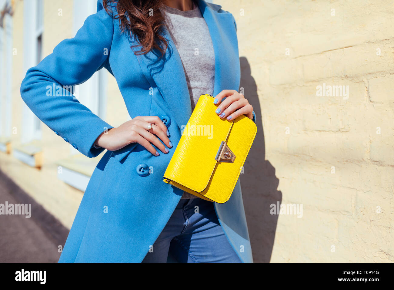 Jeune femme tenant un sac à main jaune et portant manteau bleu à la mode.  Femme printemps Vêtements et accessoires. Fashion Photo Stock - Alamy