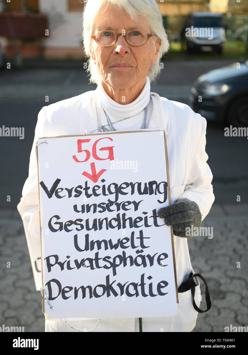 Mainz, Allemagne. Mar 19, 2019. Docteur Barbara Dohmen est titulaire d'une affiche avec l'inscription '5G - Vente aux enchères de notre santé, l'environnement, de la protection des renseignements personnels, la démocratie" sur le bord de la mise aux enchères de fréquences radio mobile 5G blocs au Mayence technology site de l'Agence fédérale des réseaux. L'abréviation 5G correspond à la 5e génération mobile. Le taux de transfert est d'environ 100 fois plus rapide que son prédécesseur, aussi appelé 4G LTE. Avec la vente aux enchères, le gouvernement fédéral peut espérer des recettes supplémentaires de plusieurs milliards. Credit : Arne Dedert/dpa/Alamy Live News Banque D'Images