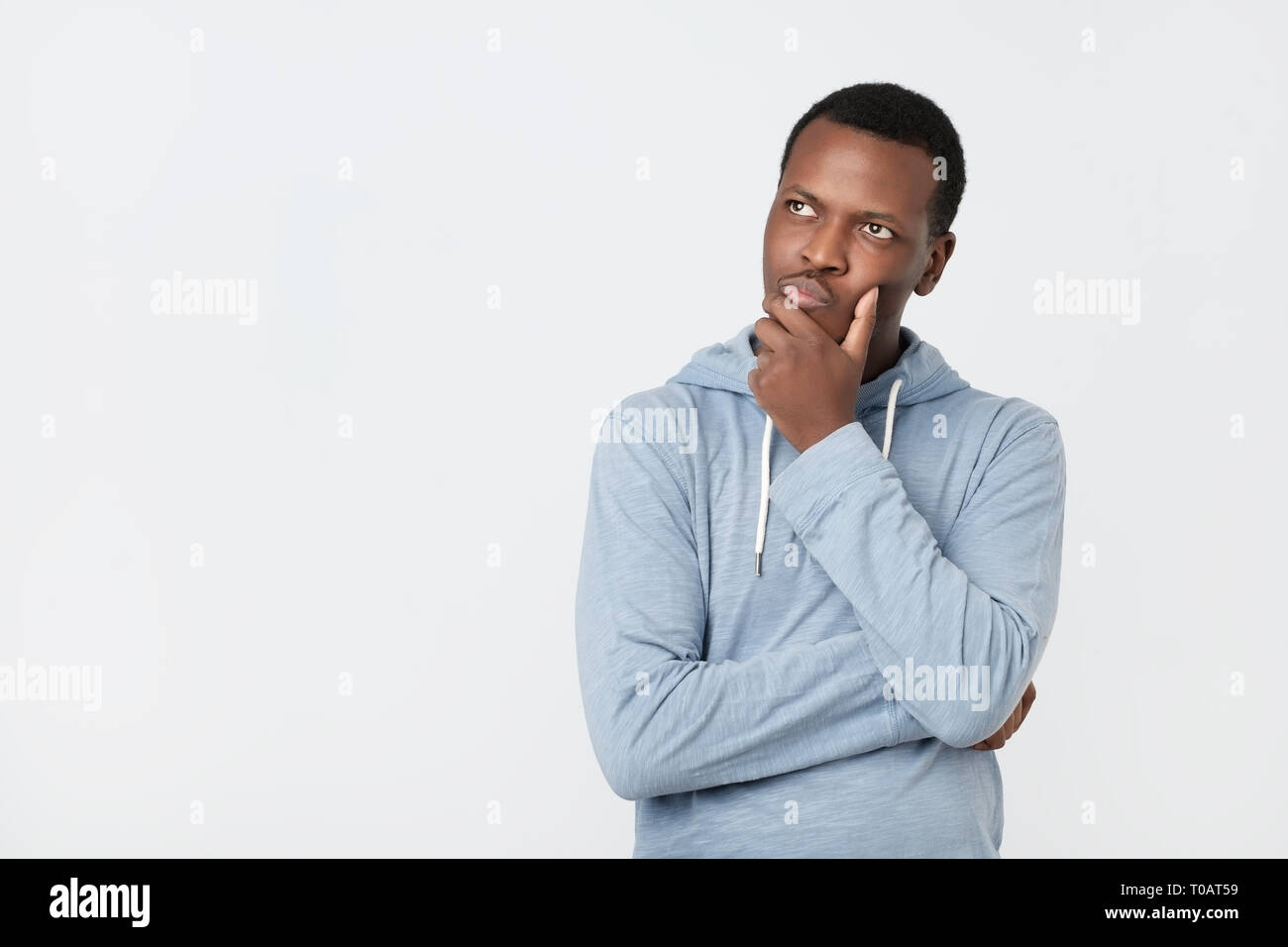 Handsome young African American man looking up avec expression sceptique et réfléchie Banque D'Images
