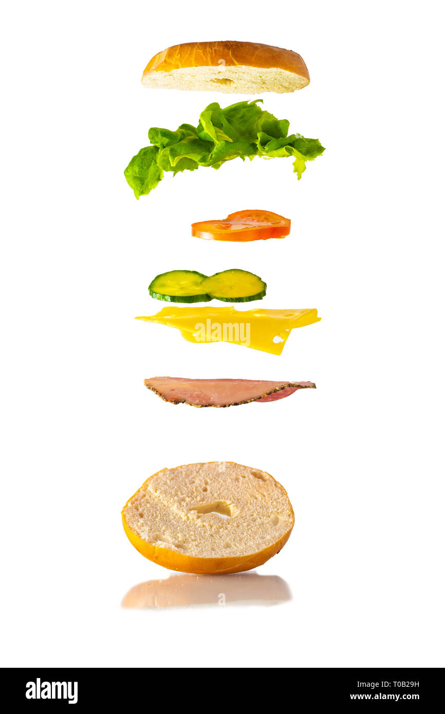 Sandwich Bagel Lévitation flottant relevant des ingrédients. Produits frais et délicieux sandwich magique. Blanc rustique / mur de brique rouge. Chips / croustilles Banque D'Images