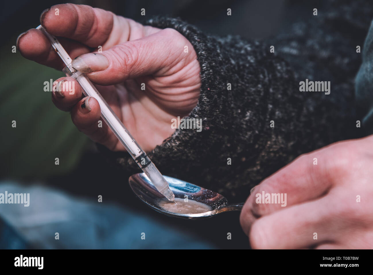 Une femme héroïnomane attire l'héroïne fraîchement préparés dans une seringue. Banque D'Images