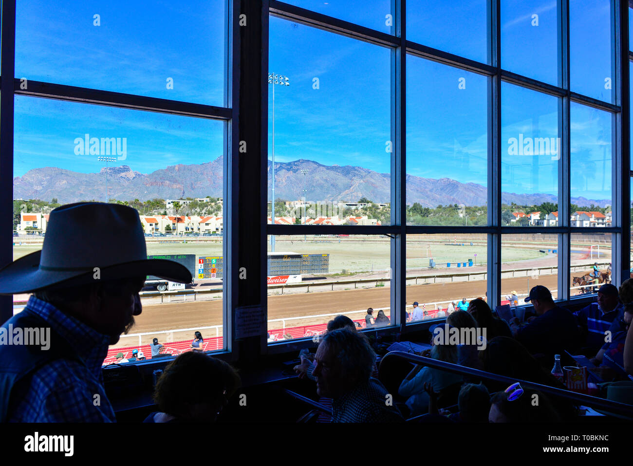 Un shiloutted Man wearing cowboy hat et d'autres sont assis dans des sièges en boîte réservée avec un service de restauration dans le pavillon au parc Rillito racetr Banque D'Images