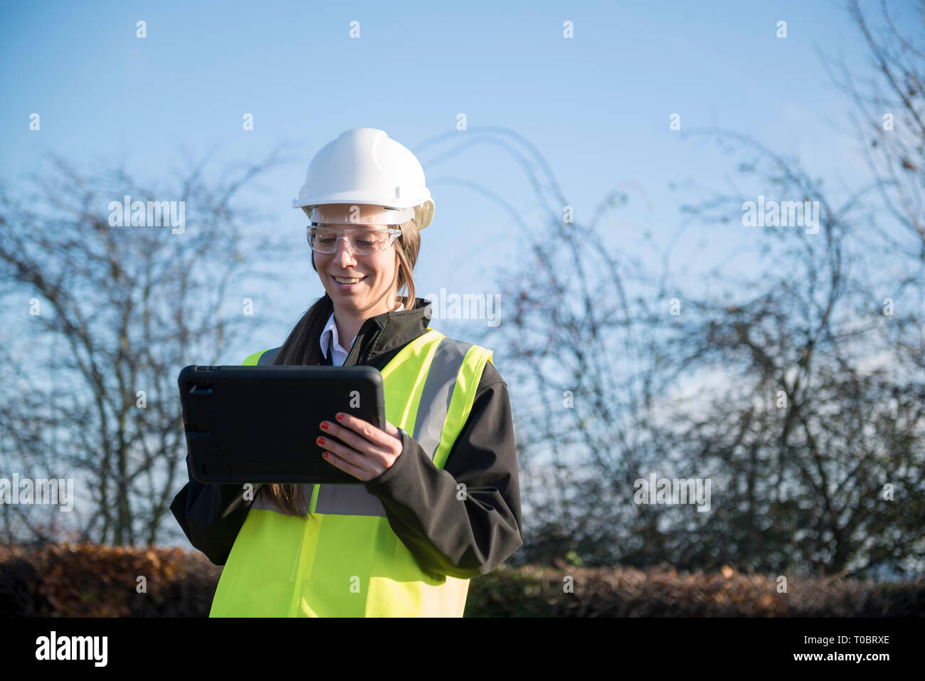 Une femme chef de projet / expert / travailleur de la construction en haute viz et l'équipement de sécurité utilise une tablette / ipad à l'entrée d'information elle s'est connecté Banque D'Images
