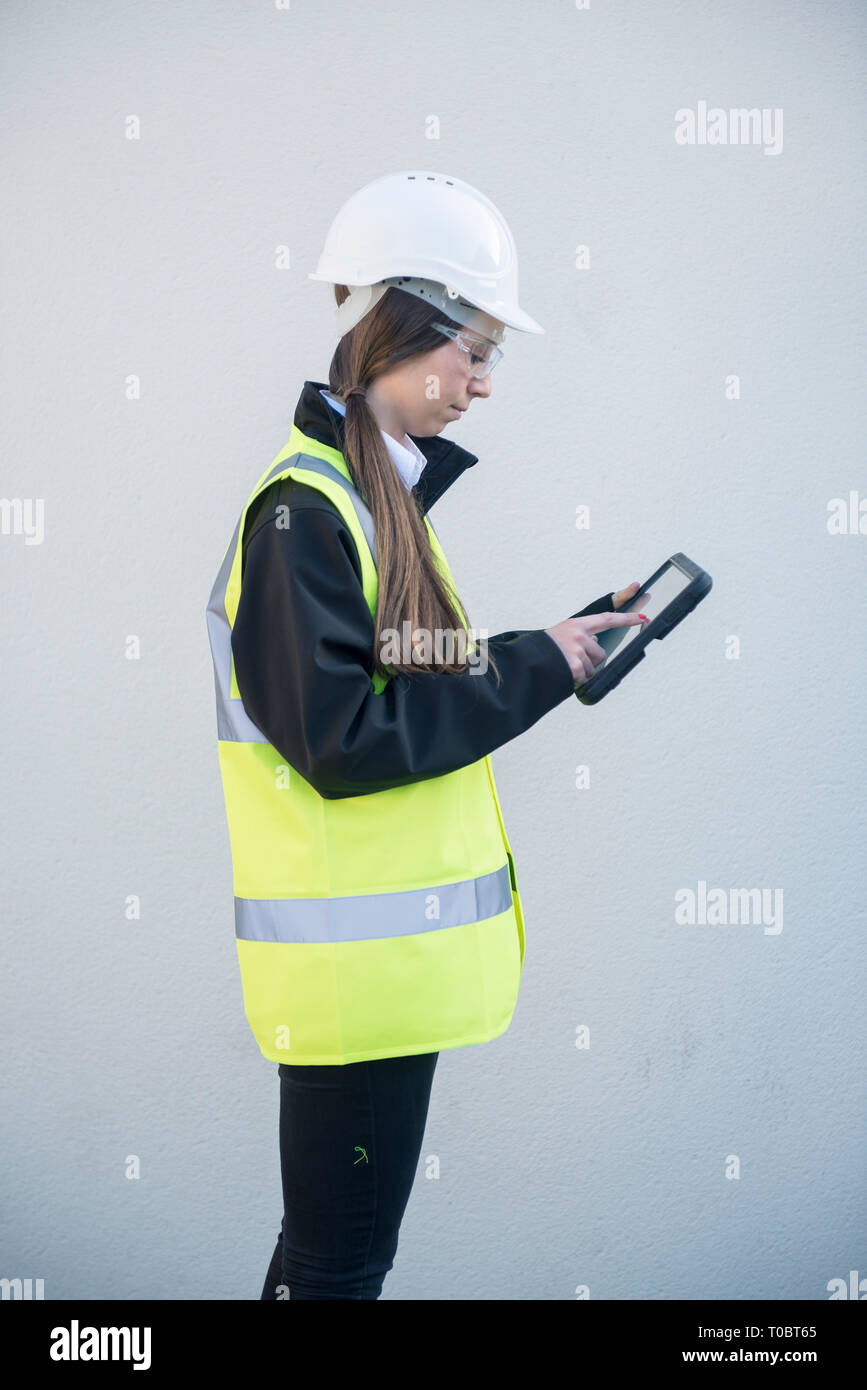 Une femme chef de projet / expert / travailleur de la construction en haute viz et l'équipement de sécurité utilise une tablette / ipad à l'entrée d'information elle s'est connecté Banque D'Images