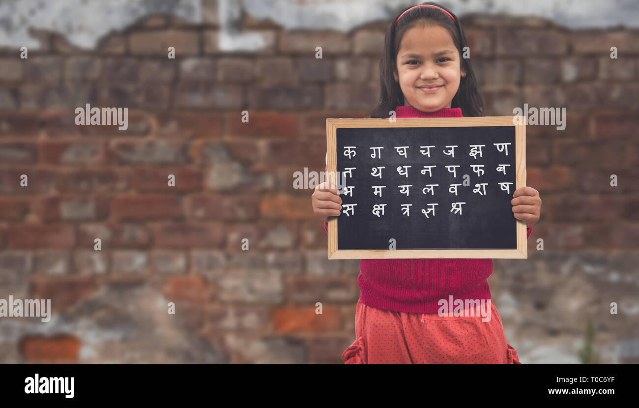 Adorable petit 8-10 ans Filles asiatiques indien souriant, tenant l'éducation tableau. Banque D'Images